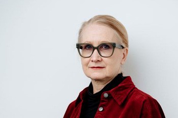 Allvarlig kvinna med glasögon och mörkröd kavaj