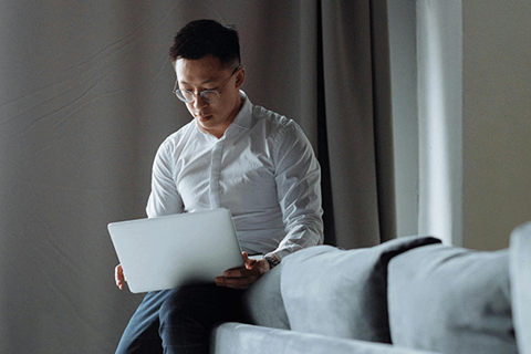 Man sitter på soffkanten med laptop