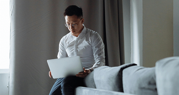 Man sitter på soffkanten med laptop