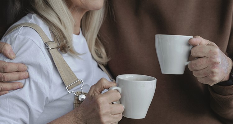 Närbild på två pensionärer som står med varsin kaffekopp